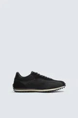 Zapatilla de cordones negra de estilo retro. Parte superior fabricada en tejido técnico y detalles en piel con acabado serraje. Suela dentada con detalle a contraste.