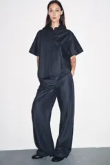 Pantalón de denim azul oscuro, de tiro medio y corte ancho, con cintura elástica en la parte trasera y cierre frontal con cremallera y botón.