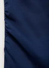 Top azul de tejido de algodón con modal y elastano, de corte entallado, con cuello asimétrico y cintura drapeada.