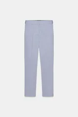 Pantalón tobillero celeste con tiro medio, cintura elástica en la espalda, bolsillos delanteros y falsos bolsillos de vivo en la espalda. Tiene aberturas laterales en el bajo y cierre frontal con cremallera, botón interior y gancho.