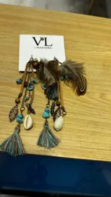 Par de caravanas colgantes con cuentas de colores, plumas marrones y dijes de metal.