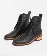 Bota corta de cuero color marrón claro, con cordones y detalles de perforaciones. Tiene un pequeño taco de madera.