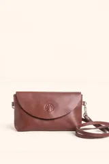 Cartera tipo sobre de cuero vacuno, con solapa frontal, cierre y broche magnético. Incluye correa larga ajustable y extraíble para usar como bandolera.