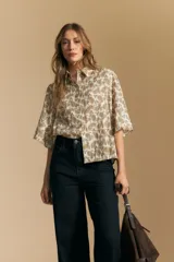 Camisa de manga corta con cuello camisero, confeccionada en tela estampada con diseño paisley en tonos negro, beige y azul.