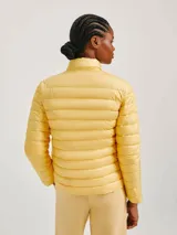 Campera puffer color crudo, confeccionada en poliéster con efecto matelassé, cuello alto y cierre frontal con cremallera.