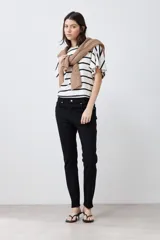 Pantalón de jean negro, corte slim fit, tiro medio y largo hasta el tobillo.