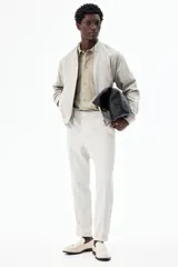 Pantalón de vestir gris claro, de corte slim fit, con cintura elástica y cordón ajustable. Presenta bolsillos laterales y traseros ribeteados, pliegues cosidos y doblez en el bajo.