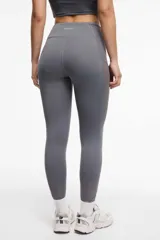 Calza deportiva larga negra con cintura alta, detalles de transparencias laterales en tul y bolsillos laterales.