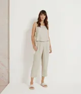 Pantalón zanahoria color beige de liocel, con pliegues delanteros, bolsillos laterales y cierre con cremallera y botón.