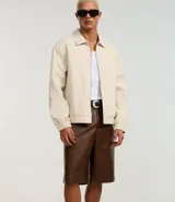 Bermuda masculina de cuero sintético color marrón, corte holgado, con cintura con trabillas, cierre tradicional, bolsillos delanteros y traseros, y efecto desteñido.