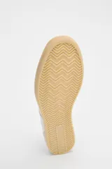 Zapatillas deportivas blancas con detalles plateados y suela color caramelo.