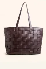 Tote bag de diseño trenzado artesanal, confeccionada en cuero vacuno color marrón oscuro. Cuenta con doble asa de hombro, cierre superior y compartimento interior forrado con bolsillos organizadores.