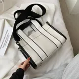 Bolso tipo tote color beige con laterales negros, doble asa corta de mano con detalles en cuero sintético negro y correa larga de hombro negra regulable y extraíble.