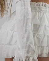 Conjunto de top con volados y falda corta con volados, ambos de color blanco.