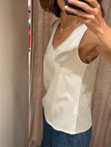 Musculosa blanca con escote en V y espalda con diseño a rayas verticales.