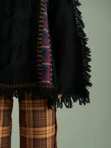 Sweater negro oversize de lana con cuello redondo, bordado central en forma de trenza, laterales con cuadrillé y mangas acampanadas desflecadas.