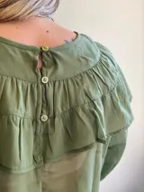 Blusa de gasa azul marino traslúcida con volados en los hombros y mangas largas abullonadas.