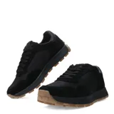 Zapatillas deportivas negras con detalles en gamuza y suela marrón.