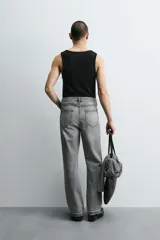 Pantalón de jean celeste de corte flare, con tiro medio, cinco bolsillos, cierre frontal con cremallera y botón, y bajo con acabado irregular.