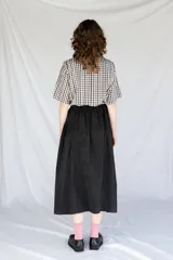 Falda midi negra con cintura elastizada y frunces en los lados.