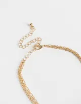 Collar corto dorado de tres cadenas con cuentas de colores y dijes de corazón y flor.