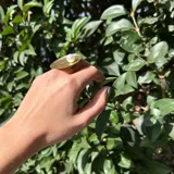 Anillo dorado con base circular texturada y perla plástica engarzada.