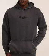 Buzo hoodie negro de algodón y poliéster, con capucha, manga larga ajustada, bajo ajustado, bolsillo canguro y estampa bordada con lettering en el pecho.