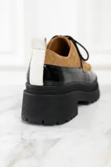 Mocasín abotinado con capellada combinada en cuero color marrón y charol negro.