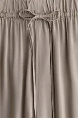 Pantalón de viscosa color beige, de corte amplio, tiro alto, cintura elastizada con cordón de ajuste, bolsillos laterales y piernas rectas.