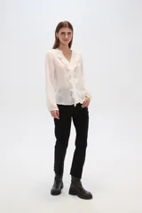 Blusa blanca de viscosa con cuello en V, volados frontales y cierre con botones.