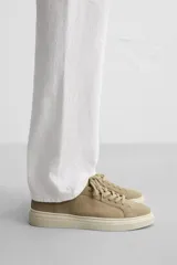 Zapatillas bajas color beige de piel serraje con cordones y suela plana color crema.