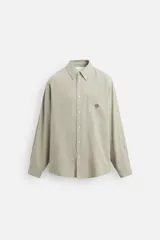 Camisa color verde claro de denim ligero de algodón, corte relaxed fit, cuello abotonado, manga larga con puño abotonado, bolsillo plastrón en pecho con bordado a contraste y cierre frontal abotonado.