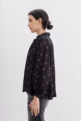 Camisa fluida negra con estampado de corazones color lila, mangas largas, cuello camisero y puños con botón.