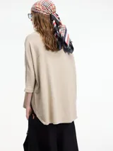 Sweater color crema de mangas 3/4, fit amplio y largo más largo en la parte trasera.