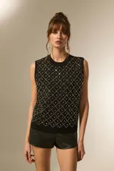 Chaleco negro sin mangas, con cuello redondo y diseño de rombos formados por strass.