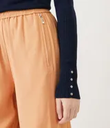 Suéter de punto color verde, con cuello barco, mangas largas y textura acanalada.