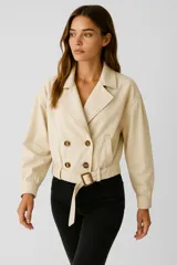Chaqueta corta color beige con doble botonadura, cuello solapa, cinturón con hebilla rectangular y mangas largas con puños elásticos.