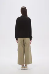 Buzo negro de manga larga con cuello polo y escote en V. Tiene un corte holgado y puños y dobladillo acanalados.