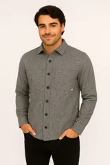 Camisa gris jaspeado de manga larga con cuello clásico, cierre frontal con botones negros, dos bolsillos de parche en el pecho y corte recto.