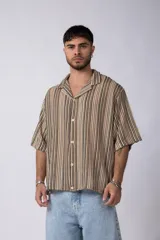 Camisa de manga corta con cuello solapa, corte holgado y estampado de rayas verticales en tonos beige, negro y rojo.