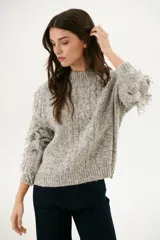 Sweater color arena de tejido de punto con cuello redondo y mangas largas con flecos.