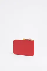 Monedero negro de cuero con cierre de cremallera y tirador de cordón amarillo. Incluye bolsillo interior y placa metálica con el logo de la marca.