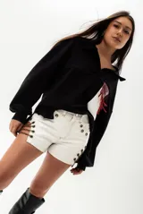 Short blanco de cuero sintético con costuras a contraste en color naranja y cadenas metálicas decorativas en los laterales.