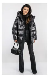 Campera oversize color blanco, confeccionada en nailon suave con un leve brillo. Cuenta con capucha, bolsillos laterales con cremallera, relleno natural y ajuste inferior con cordón. Presenta cierre frontal con cremallera de doble cursor y diseño acolchado.