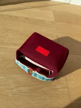 Neceser color beige de forma rectangular, con cierre superior y asa de mano.