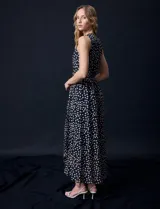 Vestido largo Donna Ricco de gasa color negro con estampado de lunares blancos, escote en V cruzado, sin mangas, cintura con lazo de ajuste y forro interno.