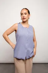 Musculosa lila con cuello redondo, sin mangas y abotonada al frente. Detalle de puntilla en el ruedo.