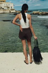 Short de denim color marrón oscuro, de tiro alto, con cinco bolsillos, calce holgado y bajo desflecado.