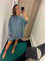 Sweater negro de punto con diseño de trenzas, corte holgado, mangas largas y bolsillos frontales. Tejido artesanalmente en Uruguay, con puños altos ajustados.