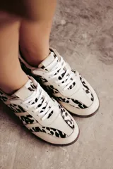 Zapatillas Adidas Samba con estampado animal print en blanco y negro, detalles en cuero beige y suela de goma color caramelo.